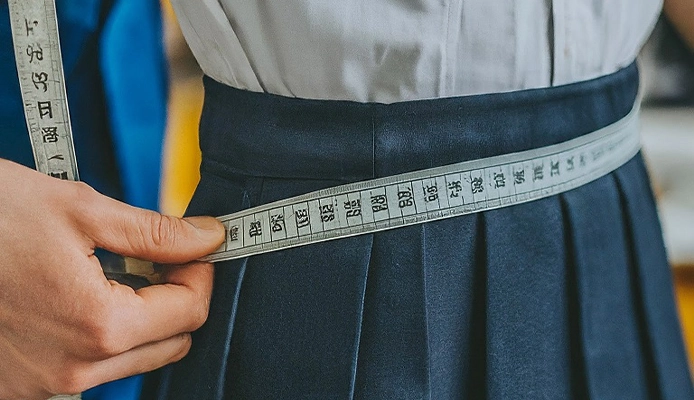 Best Guide to Size School Sports Uniforms Right Way Hands measuring the waist of a sports uniform with a tape measure to ensure proper fit and comfort.