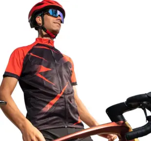 A man wearing a black & orange bike jersey and helmet, displaying a cheerful expression while riding a bicycle