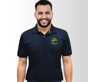A man wearing a polo shirt with GREENHILL emblem, displaying a warm smile, radiating positivity & approachability