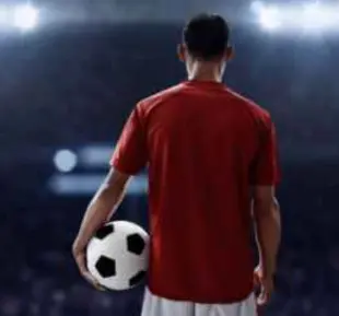 A man wearing red sportswear handles a soccer ball with confidence, as if he's about to play a skillful game