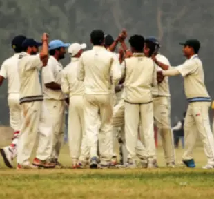A group of men in white cricket uniforms standing on a field, ready to play a match with determination and focus