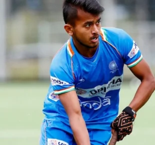 A young man energetically playing field hockey, showcasing his skills and passion in a vibrant blue attire