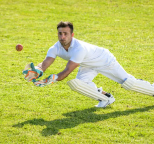 A man in white sportswear skillfully catches a ball in a vast field, showcasing his athletic ability and precision
