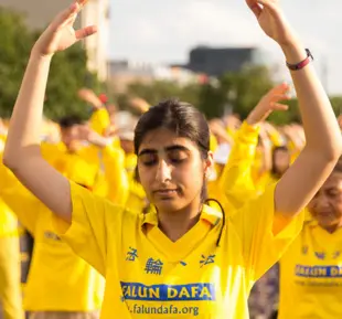 A woman wearing a vibrant yellow shirt, exuding confidence and style, stands gracefully representing FALUN DAFA org